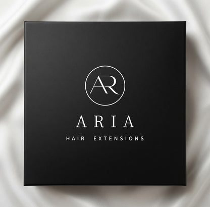 Czarne opakowanie ARIA HAIR Hair Extensions na jasnej tkaninie